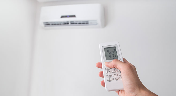 Personne allumant un climatiseur via une télécommande à écran