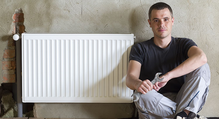 Plombier assis à côté d'un radiateur