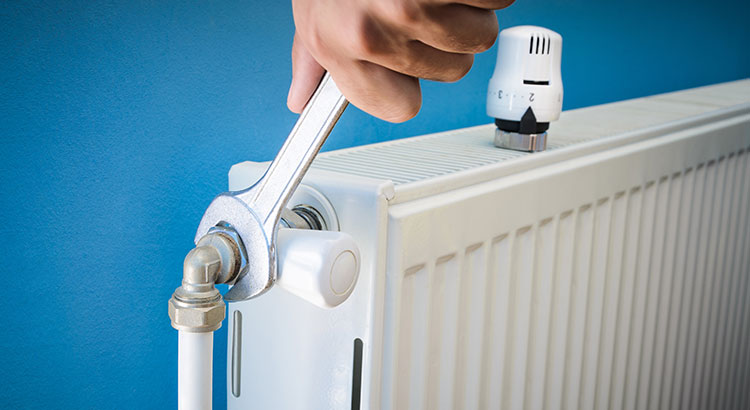 Personne resserrant le thermostat d'un radiateur