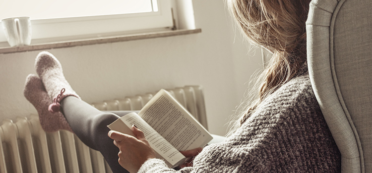 jeune femme lisant un livre devant son radiateur