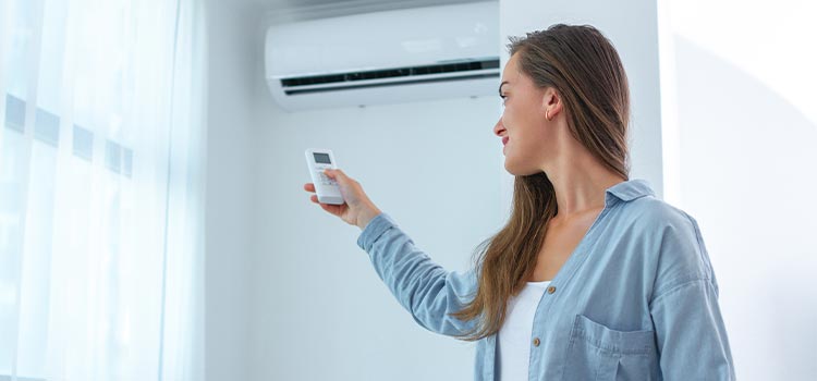 jeune femme utilisant sa climatisation murale