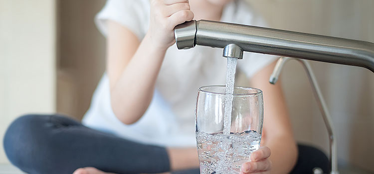 jeune femme qui se sert de l'eau du robinet