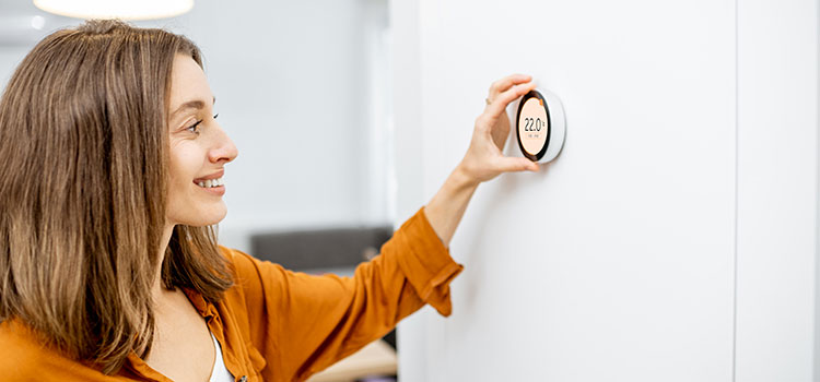 jeune femme qui utilise un thermostat de chauffage connecté