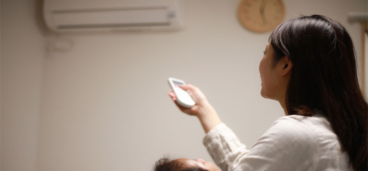 Mère utilisant une télécommande pour régler la climatisation pour son bébé